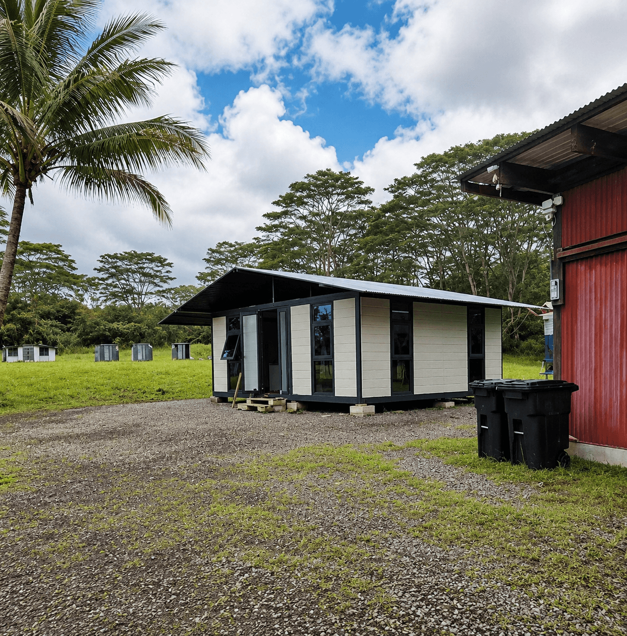 Prefab modular cabin with sloped roof installed in a tropical outdoor setting